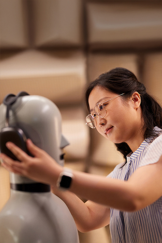 An Apple Hardware team member fitting AirPods Max headphones on a mannequin in a lab.