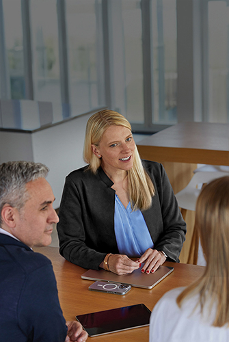 Three Apple Sales and Business Development team members talking together at a table in a common area.