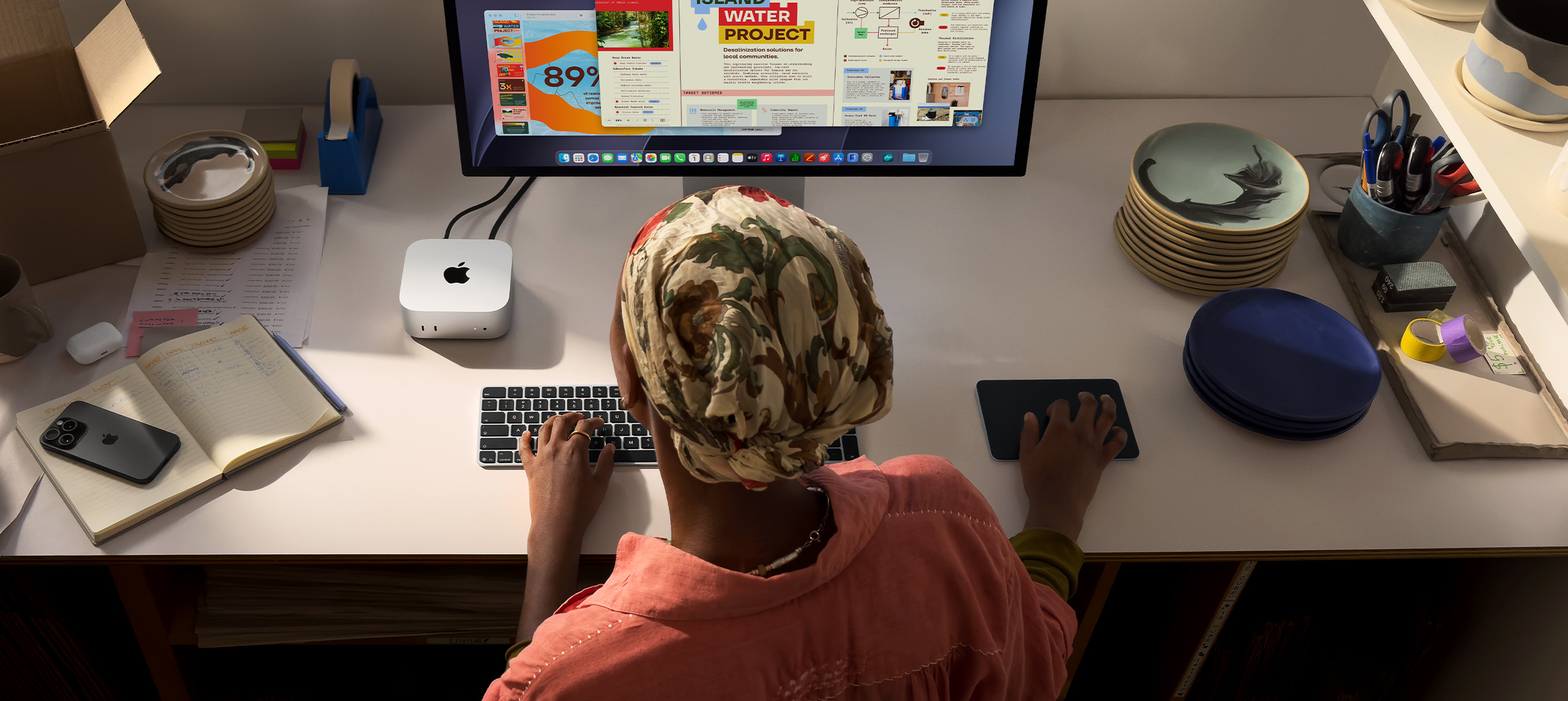 Seseorang menggunakan Mac mini di meja, yang memperlihatkan layar monitor dengan aktivitas aplikasi warna