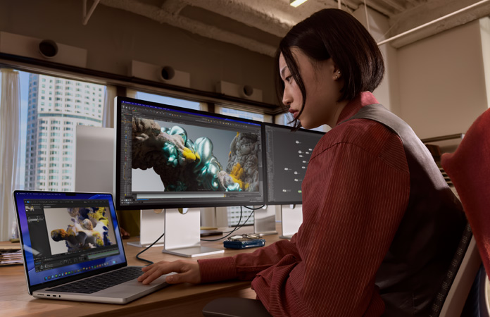 オフィスでStudio Display XDRに接続したMacBook Proを使って作業している人物