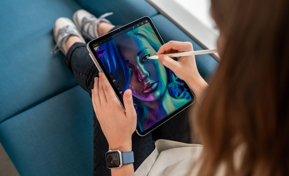 Una estudiante sentada con un iPad en el regazo usa un Apple Pencil para dibujar en la app Procreate