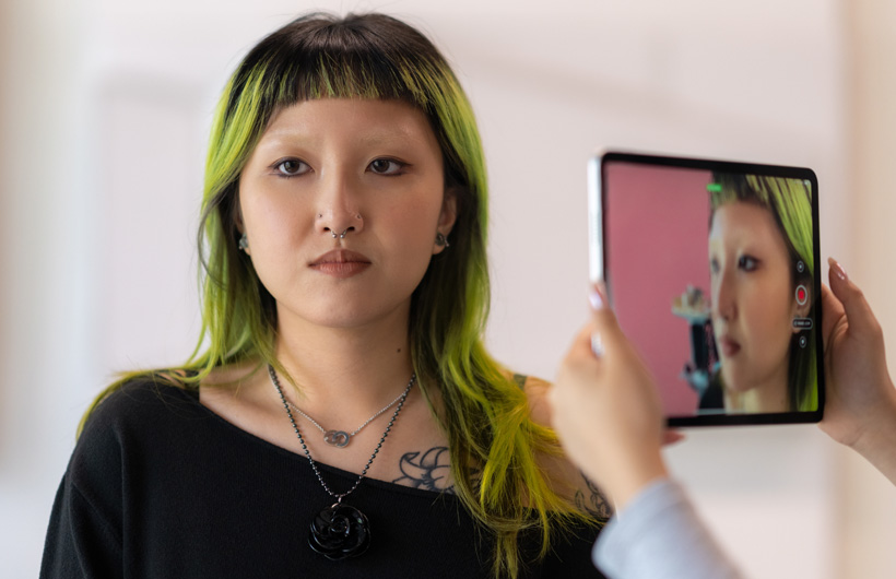 Uma estudante de cabelos verdes tem seu rosto escaneado com a câmera do iPad