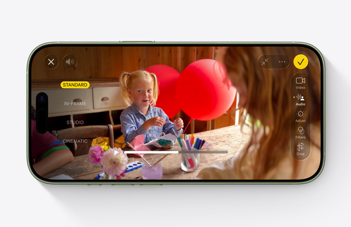 iPhone 17, etupuoli, video, jossa Äänen miksaus ‑ominaisuus on käytössä lapsen leikkiessä ilmapalloilla pöydän ääressä